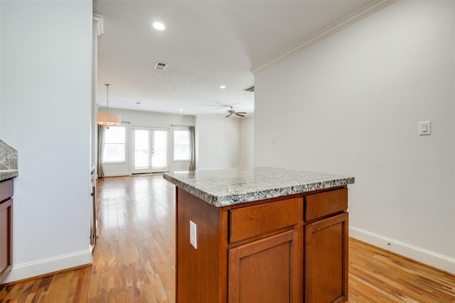 kitchen with light wood-type flooring, visible vents, a ceiling fan, open floor plan, and brown cabinetry