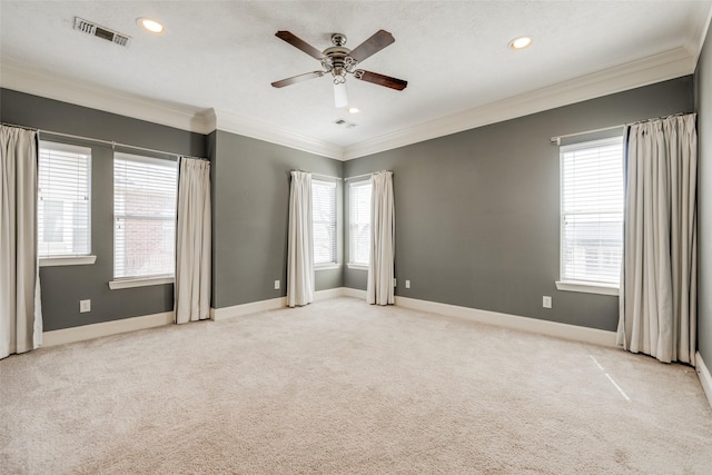 spare room with visible vents, baseboards, light colored carpet, and ornamental molding