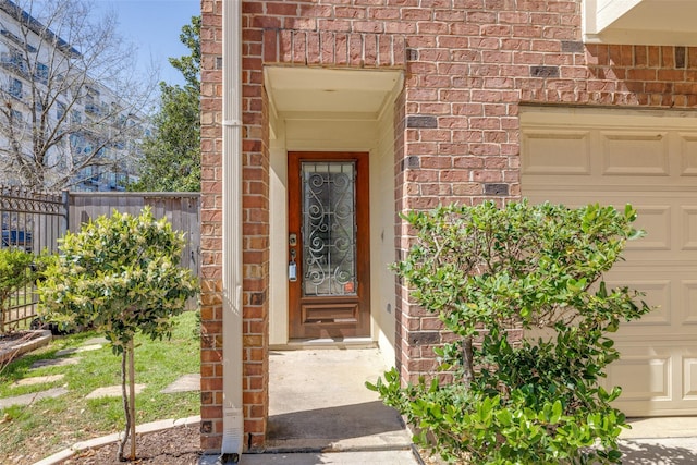 entrance to property with a garage, fence, and brick siding