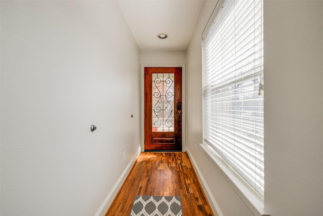 doorway with dark wood-type flooring and baseboards