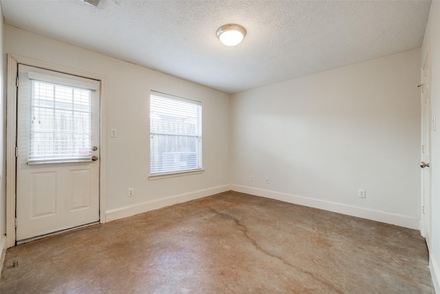 spare room with baseboards and a textured ceiling