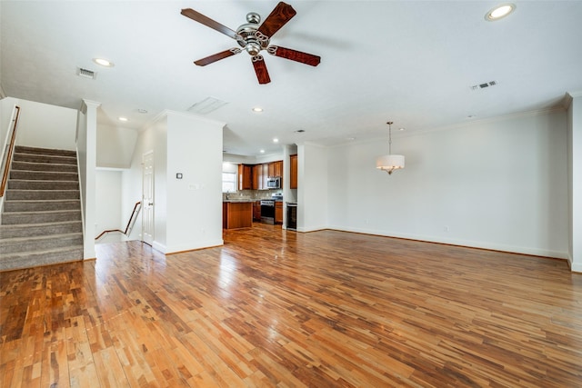 unfurnished living room featuring visible vents, stairway, crown molding, and wood-type flooring