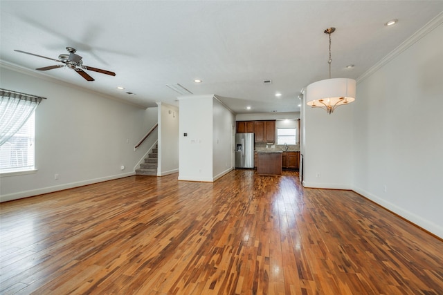 unfurnished living room with stairway, baseboards, dark wood finished floors, and crown molding