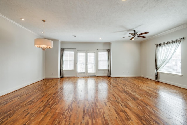 unfurnished room with baseboards, wood-type flooring, a textured ceiling, and crown molding