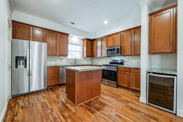 kitchen with beverage cooler, visible vents, appliances with stainless steel finishes, and crown molding