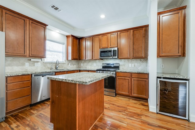 kitchen featuring a sink, beverage cooler, light wood finished floors, and stainless steel appliances