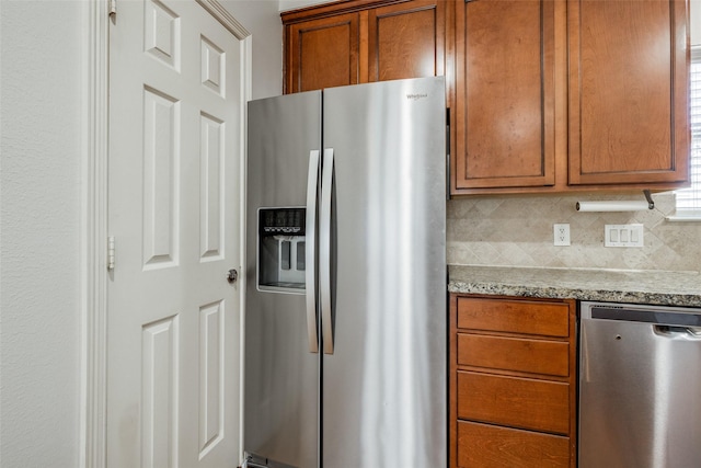 kitchen with light stone counters, decorative backsplash, brown cabinets, and stainless steel appliances