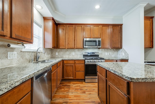 kitchen featuring a sink, ornamental molding, light wood-style floors, and stainless steel appliances