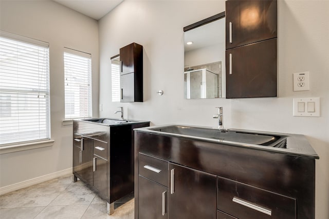 kitchen with dark brown cabinetry, light tile patterned floors, baseboards, and a sink