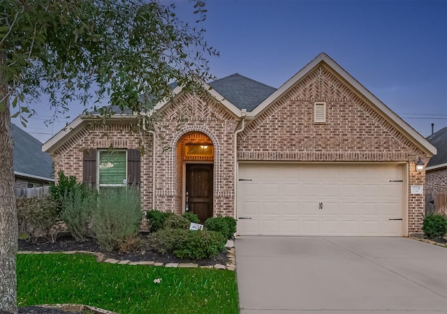 view of front of property with an attached garage, brick siding, driveway, and roof with shingles