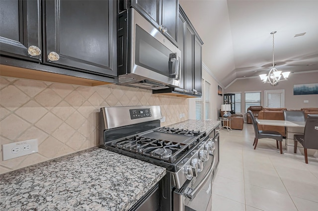 kitchen with open floor plan, stainless steel appliances, light tile patterned flooring, dark cabinets, and vaulted ceiling