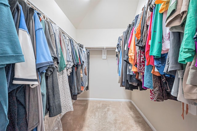 walk in closet with vaulted ceiling and carpet flooring