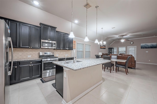 kitchen featuring tasteful backsplash, vaulted ceiling, light tile patterned flooring, stainless steel appliances, and a sink