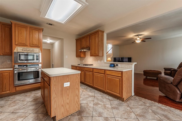 kitchen with visible vents, stainless steel appliances, light countertops, under cabinet range hood, and open floor plan