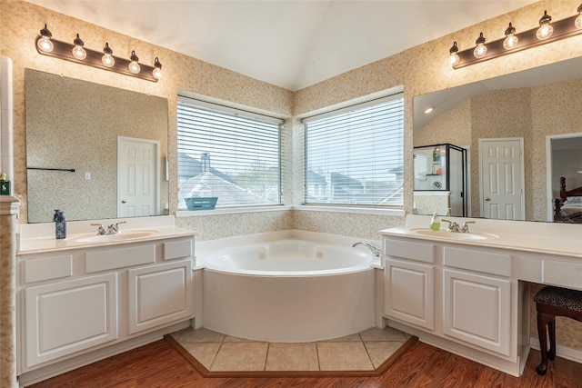 bathroom featuring wallpapered walls, lofted ceiling, a garden tub, and a sink