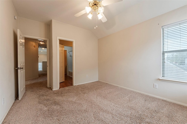 unfurnished bedroom with baseboards, lofted ceiling, light colored carpet, and ceiling fan