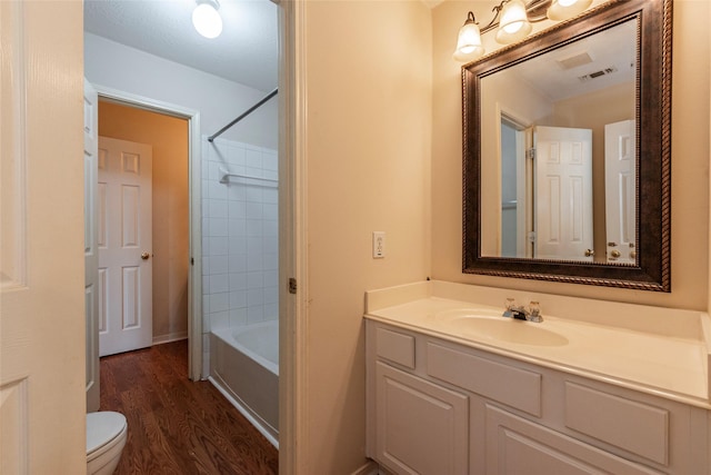 bathroom featuring vanity, wood finished floors, visible vents, tub / shower combination, and toilet