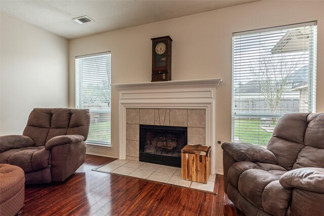 living area featuring wood finished floors, visible vents, and a tile fireplace