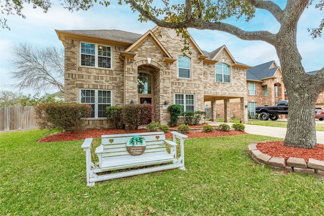 traditional-style house with brick siding, concrete driveway, fence, and a front lawn