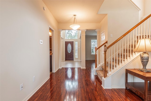 foyer entrance featuring stairway, wood-type flooring, baseboards, and ornate columns