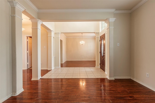 hallway with decorative columns, a notable chandelier, wood finished floors, and ornamental molding