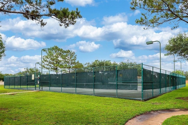 view of sport court with a lawn and fence