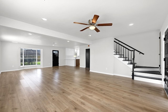 unfurnished living room with a ceiling fan, baseboards, light wood-style flooring, recessed lighting, and stairs