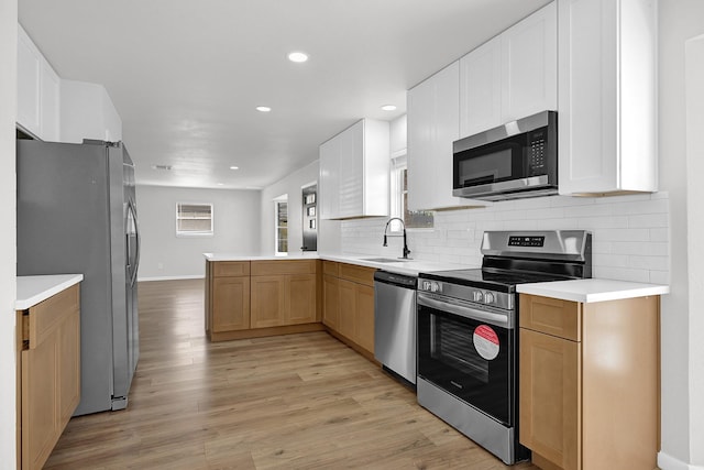 kitchen featuring a sink, stainless steel appliances, tasteful backsplash, and light wood finished floors