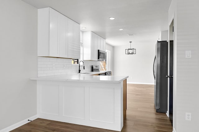 kitchen with a peninsula, light countertops, appliances with stainless steel finishes, and a sink