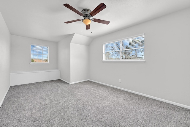 carpeted empty room featuring lofted ceiling, a ceiling fan, baseboards, and a wealth of natural light