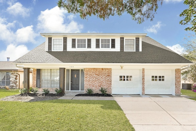 traditional-style house featuring a front yard, driveway, roof with shingles, a garage, and brick siding