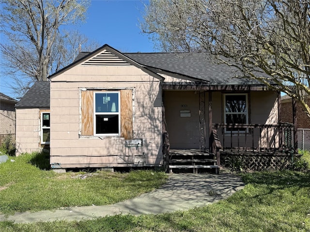 bungalow-style house featuring a porch, a front lawn, and roof with shingles