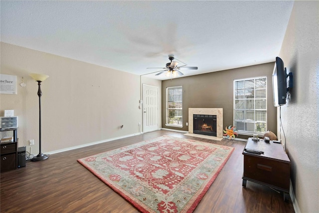 living room with a fireplace with flush hearth, baseboards, ceiling fan, and wood finished floors