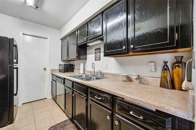 kitchen with dishwasher, light countertops, freestanding refrigerator, light tile patterned flooring, and a sink