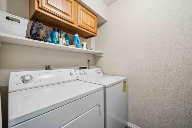 laundry room with cabinet space, washing machine and dryer, and a textured wall