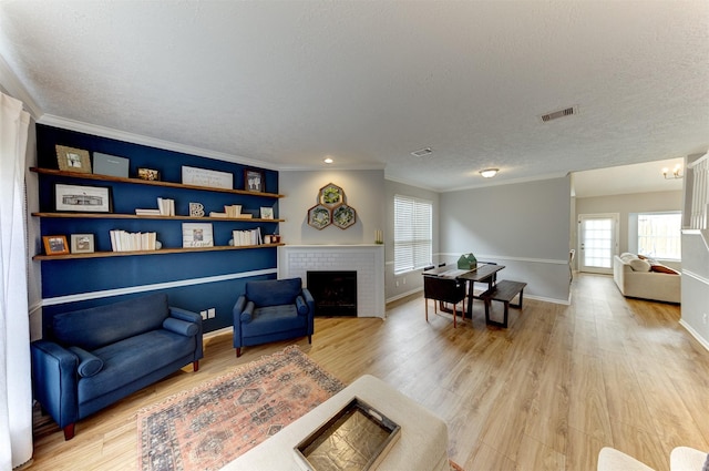 living area featuring light wood-style flooring, a fireplace, and visible vents