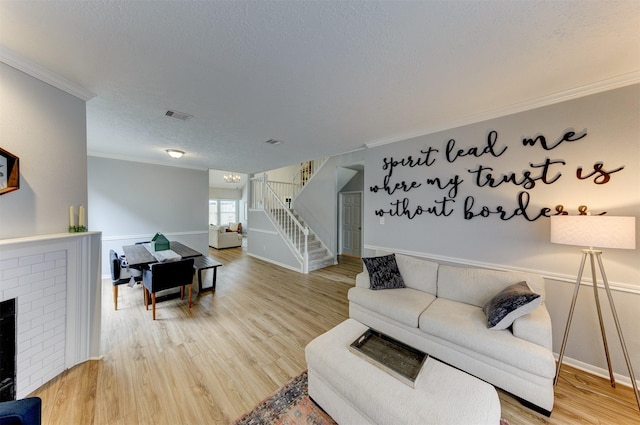 living area featuring visible vents, crown molding, stairway, light wood-type flooring, and a textured ceiling