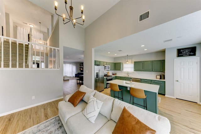 living area with light wood-type flooring, baseboards, visible vents, and a chandelier