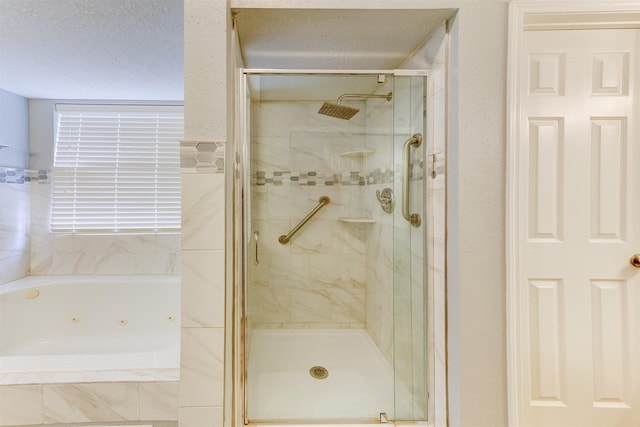 full bathroom featuring a stall shower, a jetted tub, and a textured ceiling