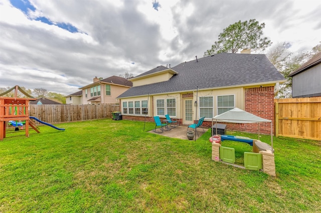 back of house with a patio, a fenced backyard, a playground, a yard, and brick siding