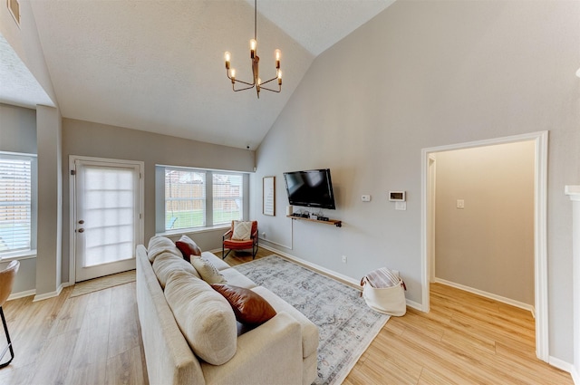 living area featuring a chandelier, high vaulted ceiling, baseboards, and wood finished floors