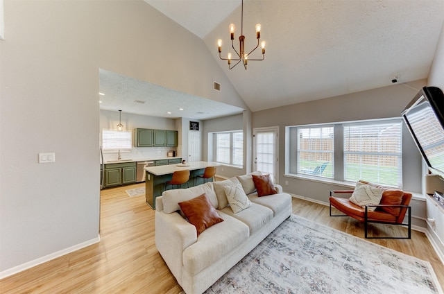 living area with visible vents, baseboards, high vaulted ceiling, and light wood finished floors