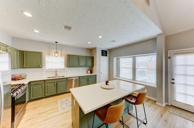 kitchen with visible vents, green cabinetry, light wood-style flooring, a sink, and stainless steel appliances