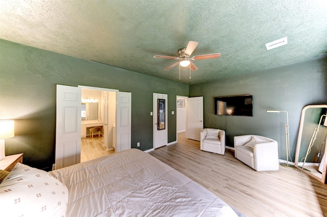 bedroom featuring a textured ceiling, wood finished floors, visible vents, and baseboards