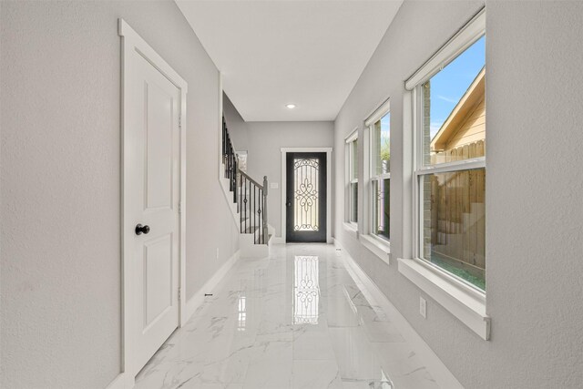 foyer with marble finish floor, baseboards, and stairway