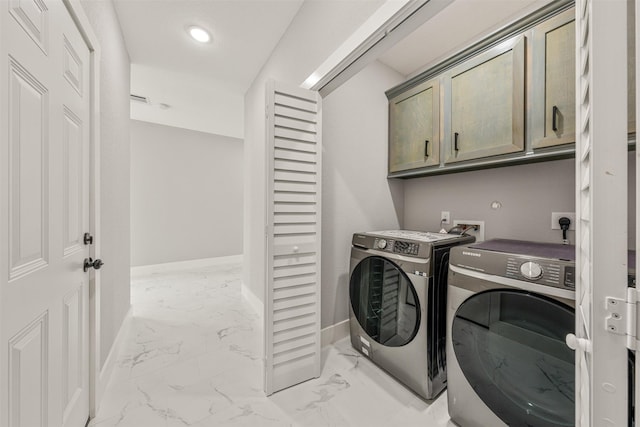 clothes washing area featuring washer and dryer, marble finish floor, baseboards, and cabinet space