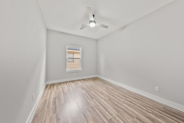 spare room with baseboards, light wood-type flooring, and a ceiling fan