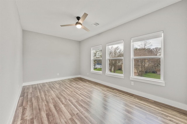 spare room with wood finished floors, baseboards, a ceiling fan, and visible vents