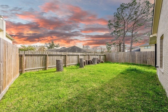 yard at dusk featuring a fenced backyard