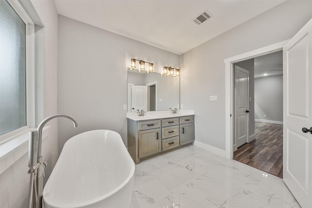 full bathroom featuring visible vents, baseboards, double vanity, a freestanding tub, and marble finish floor